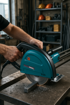 Take the product from the reference image (preserve its exact shape, colours, and brand details) and place it naturally in this setting at a realistic scale, with no people in the frame: photorealistic photo of a person's hands operating a black and red circular metal saw on an industrial workbench in a professional workshop, metal shavings, organized construction environment, natural daylight, sharp focus, product-in-use